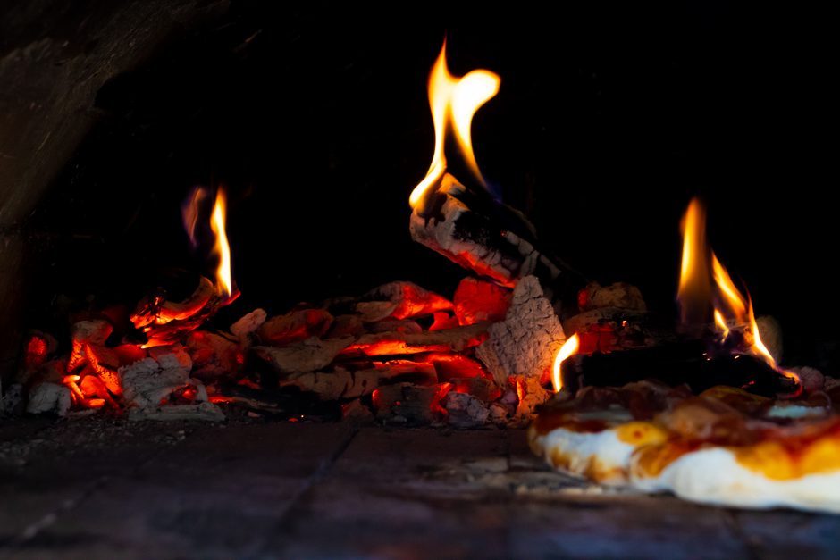 Čerstvá pizza vyberaná z pece na drevo