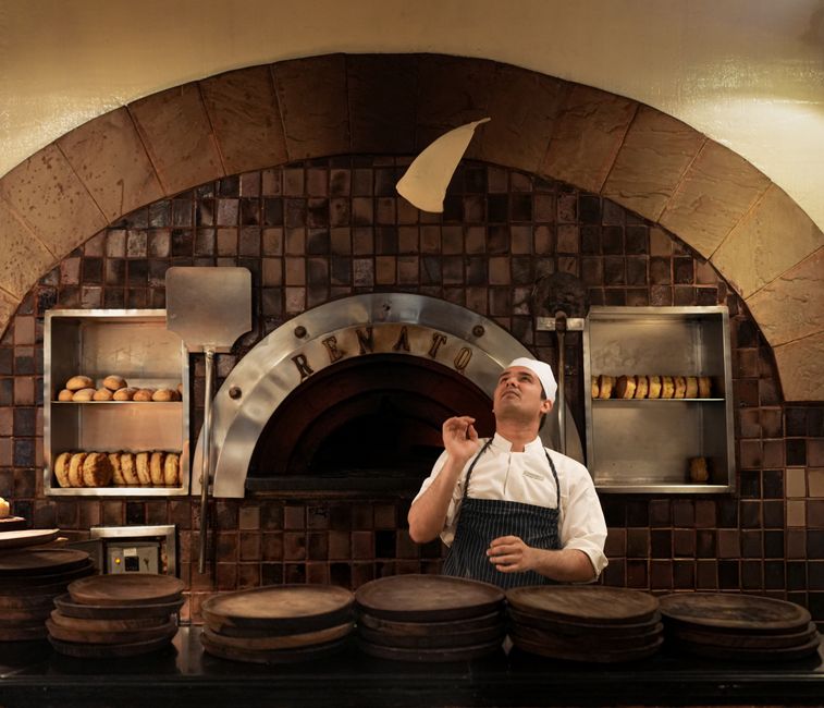 Tím Pizza Horec pripravuje pizzu pri peci na drevo